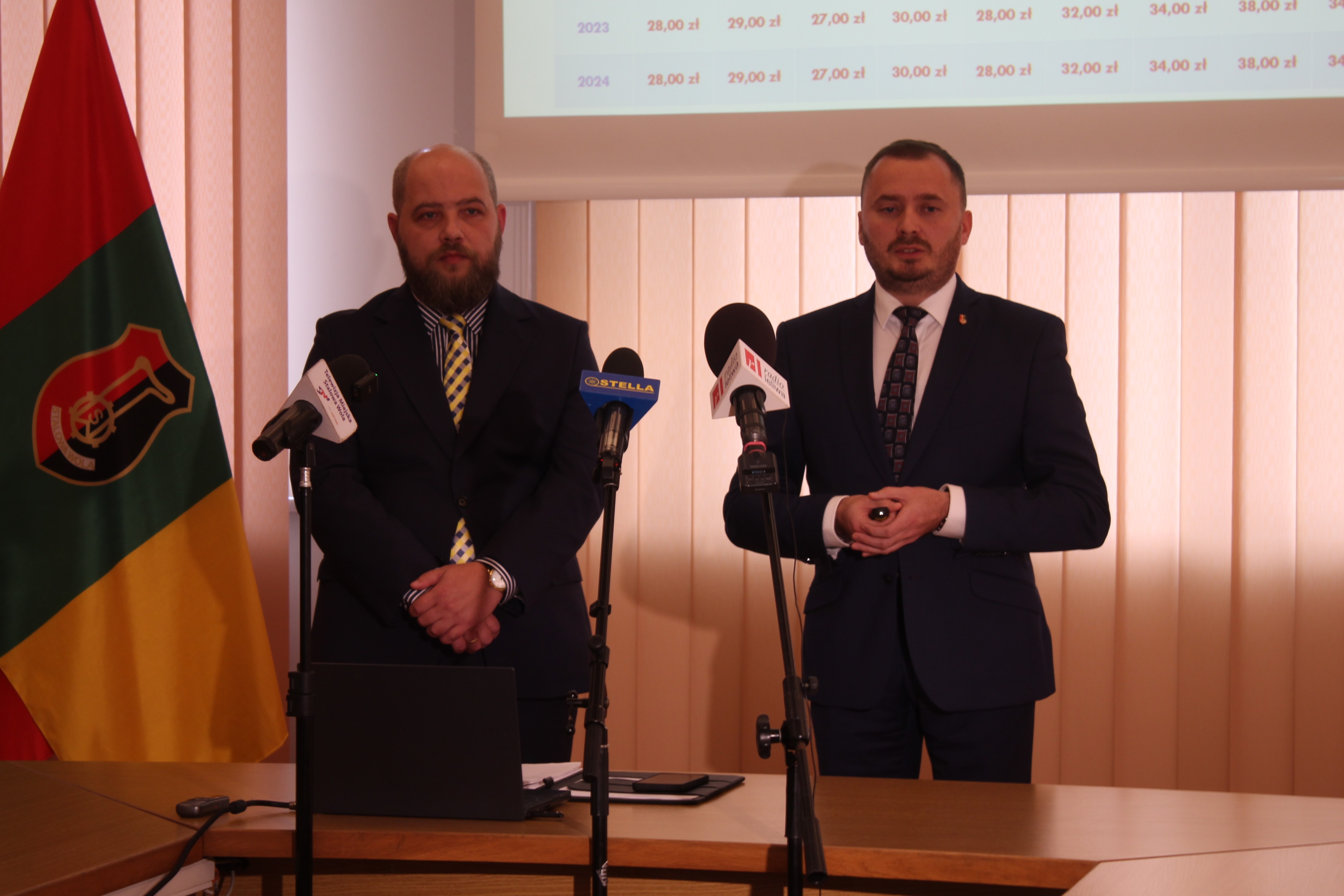 Konferencja prasowa, dwie osoby, mikrofony, flaga Stalowej Woli